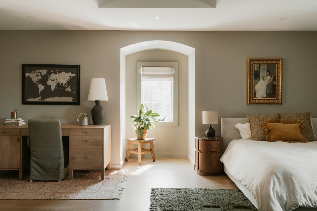 Bedroom with a desk, an arched window, and a bed